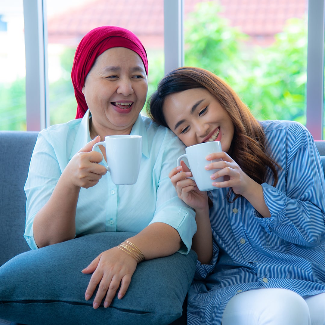 Mother and daughter smiling and drinking coffee together