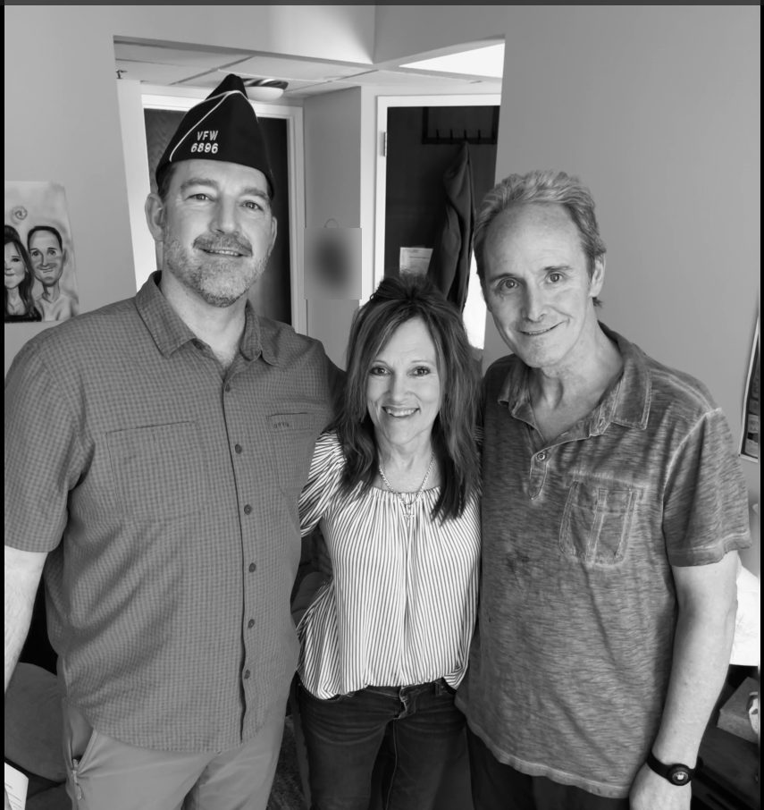 A Navy veteran and a family member smile with a VFW Post 6896 member after a Lily Hospice pinning ceremony