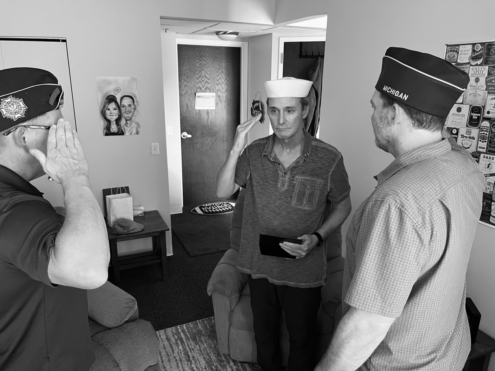 A member of VFW Post 6896 salutes a Navy veteran during a Lily Hospice pinning ceremony at the veteran's home